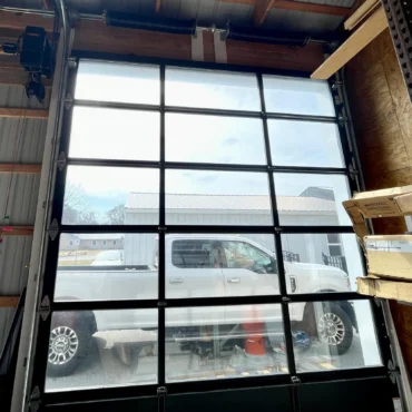 Interior view of a modern glass commercial garage door with aluminum frame, installed by Triple A Garage Door in Massachusetts