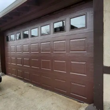 Carriage-style residential garage door with decorative hardware