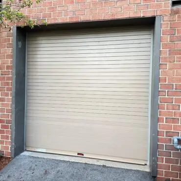 Commercial roll-up garage door installation on brick building in Massachusetts